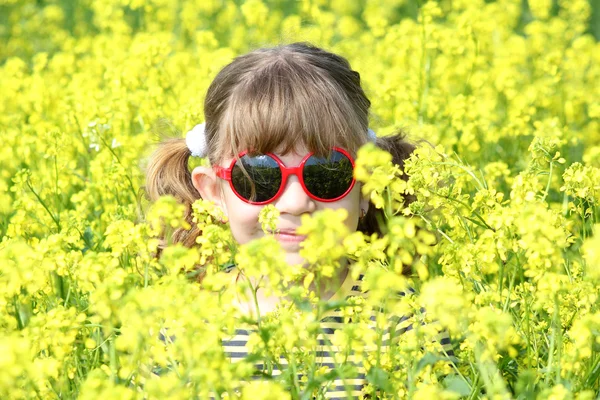 Menina se escondendo no campo de flores amarelas — Fotografia de Stock