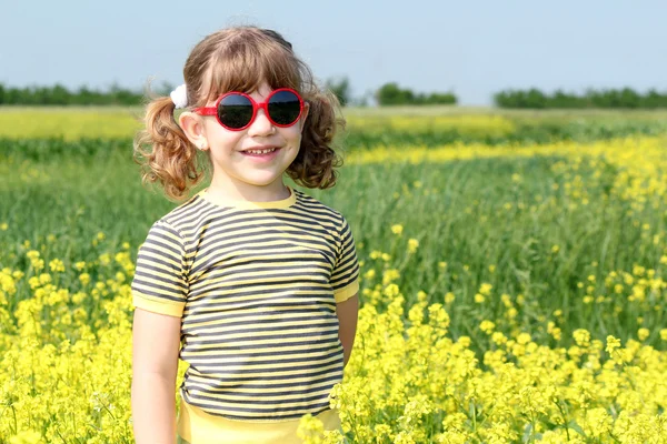 黄色の花のフィールドでポーズをとって小さな女の子 — ストック写真