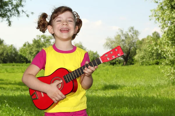 Счастливая девочка играет на гитаре в парке — стоковое фото