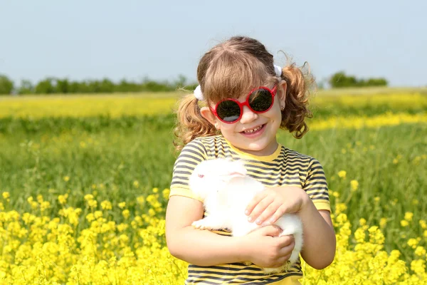 Little girl with bunny pet in yellow field — Stock Photo, Image