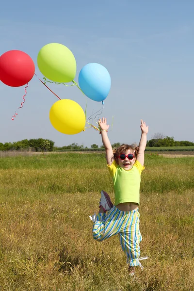 Little girl with colorful balloons jumping — Stock Photo, Image