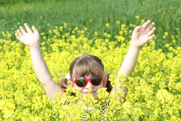 Kaldır ellerini sarı çiçek alanı ile küçük kız — Stok fotoğraf
