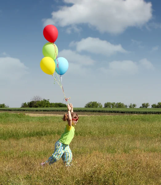 Kleines Mädchen rennt mit bunten Luftballons — Stockfoto