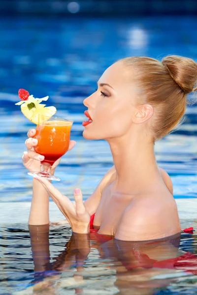 Menina bonita bebendo uma bebida tropical em uma piscina — Fotografia de Stock