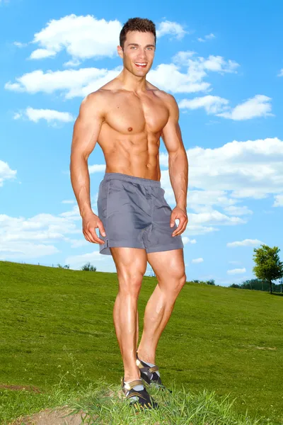 Полное тело мускулистого человека, стоящего на траве — стоковое фото