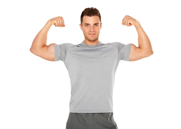 Здоровый и мускулистый мужчина, размахивающий бицепсами на белом — стоковое фото