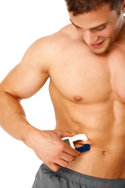 Красивый мужчина измеряет уровень жира на своем теле — стоковое фото