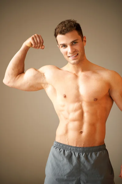 Retrato de homem desportivo muscular, ele mostra seu bíceps — Fotografia de Stock