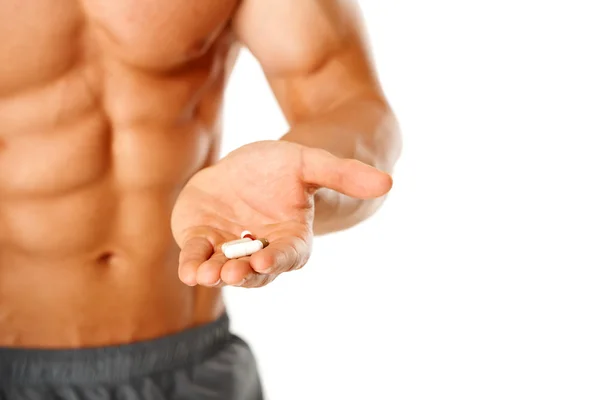 Close up de torso homem muscular com a mão cheia de pílulas — Fotografia de Stock