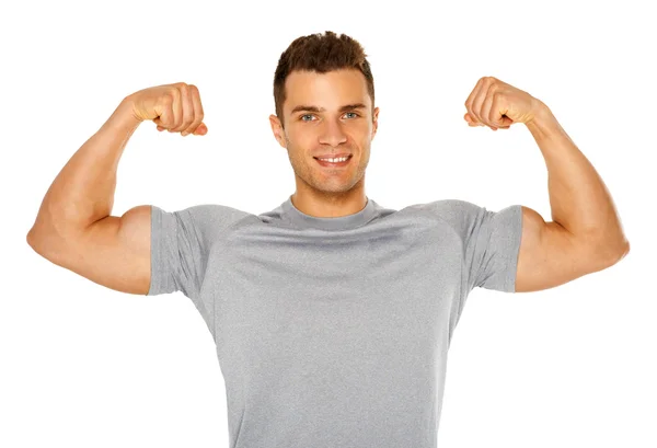 Fit a svalnatý muž protahuje jeho biceps na bílém pozadí — Stock fotografie