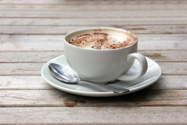 Šálek cappuccino na dřevěné laťkové stůl — Stock fotografie