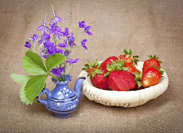 Blumenstrauß in einer Keramik-Teekanne und Erdbeeren in einem wic — Stockfoto