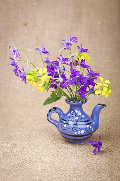 Bukett blommor i en keramik tekanna i bakgrunden av den — Stockfoto