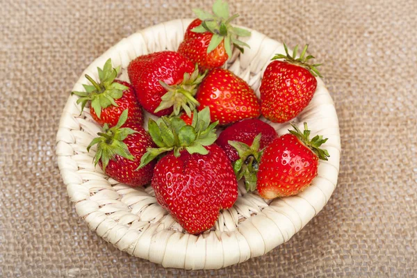 Erdbeeren in einem Weidenkorb auf dem Hintergrund der Leinwand — Stockfoto