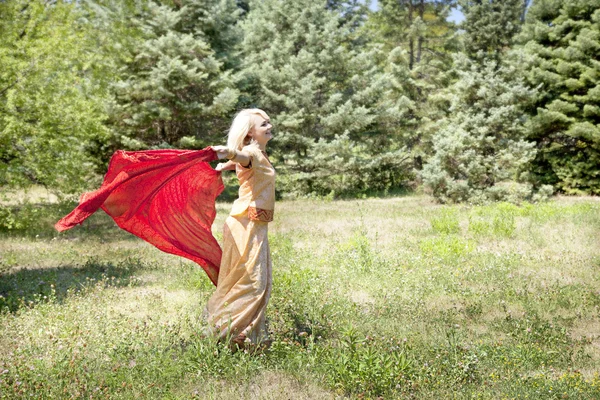 Flicka med röd scarf danser i trädgården — Stockfoto