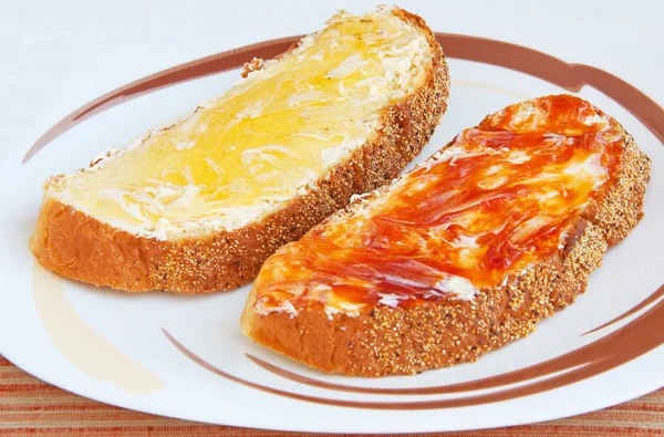 Два куска хлеба с маслом и джемом — стоковое фото
