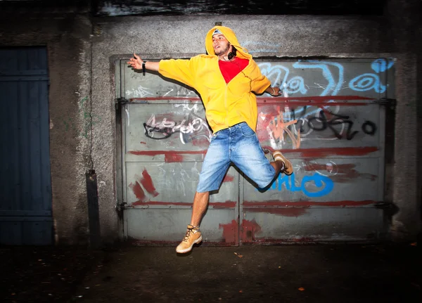 Young man jumping on grunge wall — Stock Photo, Image