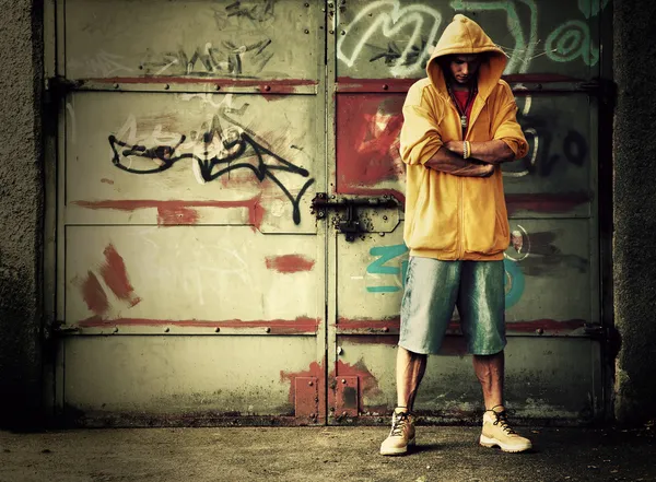 Jonge man in hooded sweatshirt op grunge muur — Stockfoto
