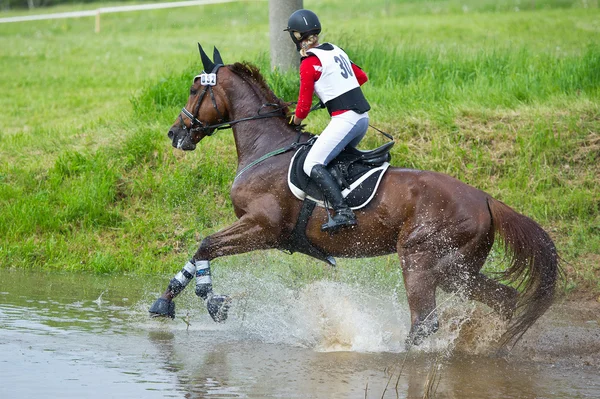 Eventer on horse is overcomes the Water jump — Stock Photo, Image