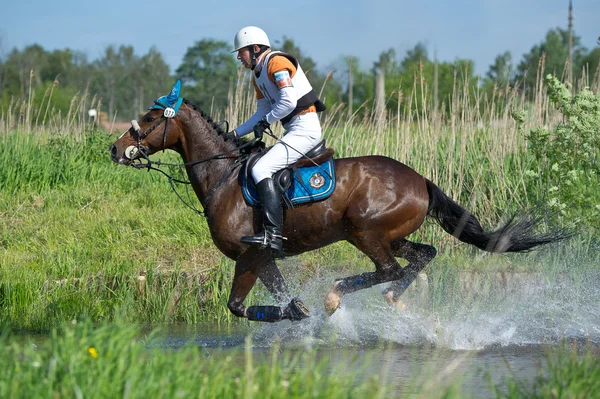 Cavaleiro a cavalo está negociando salto de água cross-country — Fotografia de Stock