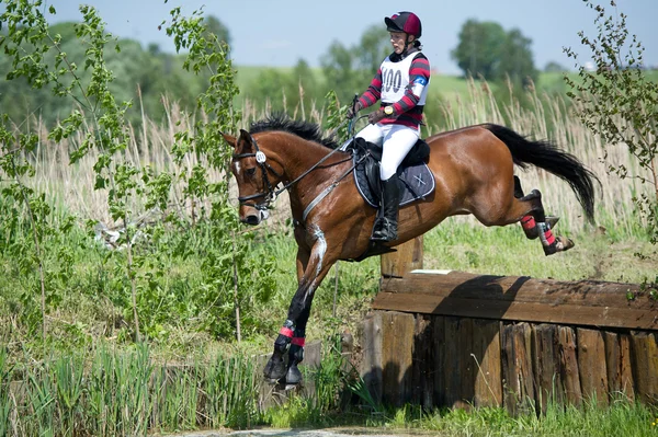 Kadın eventer at üzerinde açılan çit olarak su atlama olduğunu — Stok fotoğraf