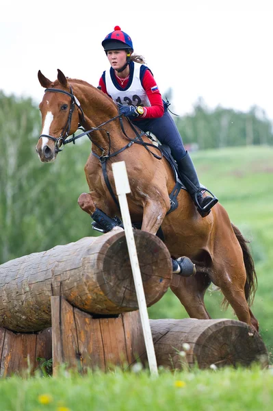 Desporto equestre. Mulher eventer em cavalo negociando cross-country Obstáculo fixo Cerca de registro — Fotografia de Stock