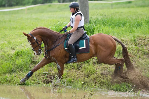 Eventer on horse negotiating Water jump — Stock Photo, Image