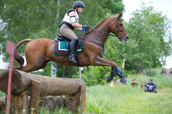 Equestrian sport. Woman eventer on horse negotiating cross-country Fixed obstacle Log fence — Stock Photo, Image