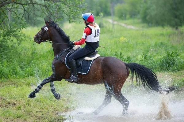 Mujer eventer a caballo se supera el salto de agua — Foto de Stock