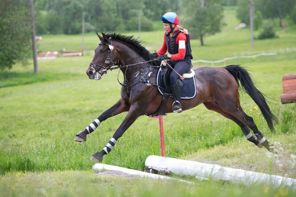 Vrouw op paard is overwint de cross-country hek — Stockfoto