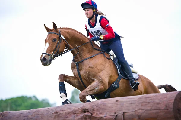 RID sport. kvinna fälttävlan på häst förhandlar cross-country fasta hinder log staket Stockbild