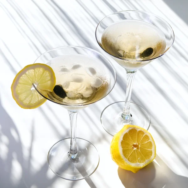 Вид сверху алкогольный коктейль мартини с желтым лемоном на белом с тенями — стоковое фото