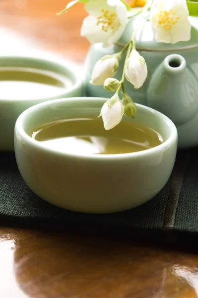 Zelený čaj s Jasmín v poháru a konvici na dřevěný stůl — Stock fotografie
