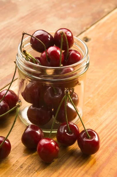Cherry v sklenice izolovaných na dřevěné pozadí — Stock fotografie