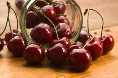 Cherry in glass jar isolated on the wooden background