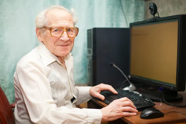 Sorridente uomo anziano vicino al computer — Foto Stock