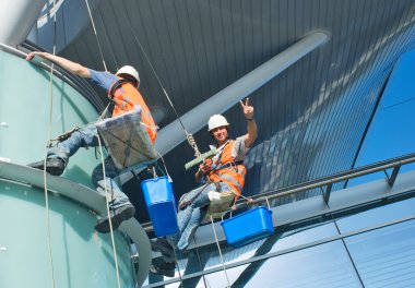 A man cleaning windows on a high rise building clipart