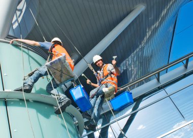 A man cleaning windows on a high rise building clipart