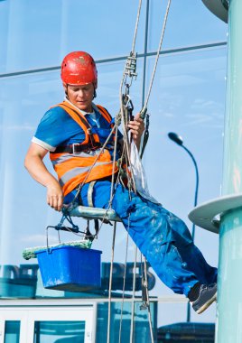 A man cleaning windows on a high rise building clipart
