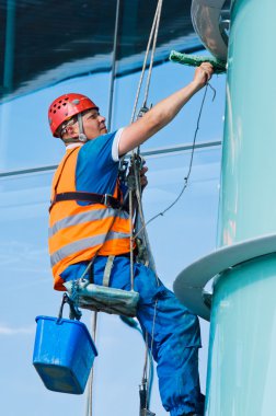 A man cleaning windows on a high rise building clipart