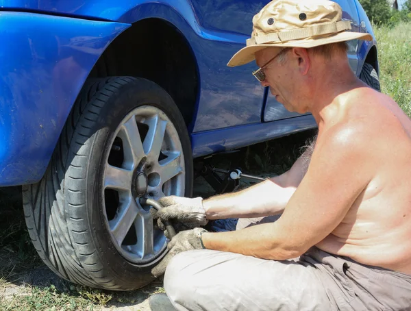 Hombre mayor cambiando una rueda de su coche —  Fotos de Stock