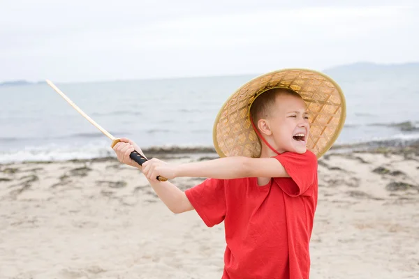 Плачущий мальчик играет с самурайским мечом — стоковое фото