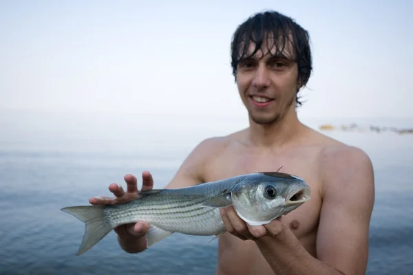 Pescatore tiene una triglia di mare — Foto Stock