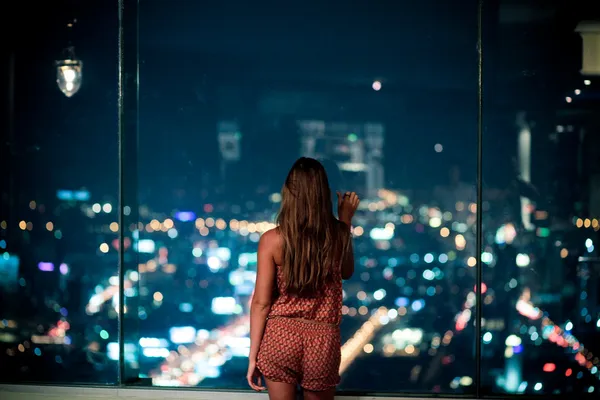 Femme observant la ville la nuit — Photo