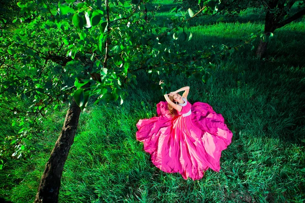 Vrouw in een lange roze jurk — Stockfoto
