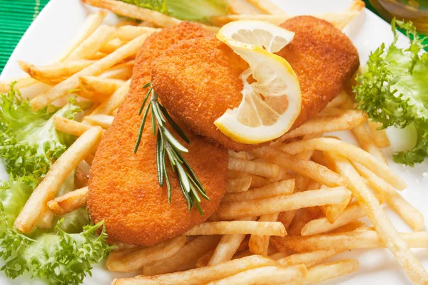 Breaded fish steaks with french fries, lemon and lettuce — Stock Photo, Image
