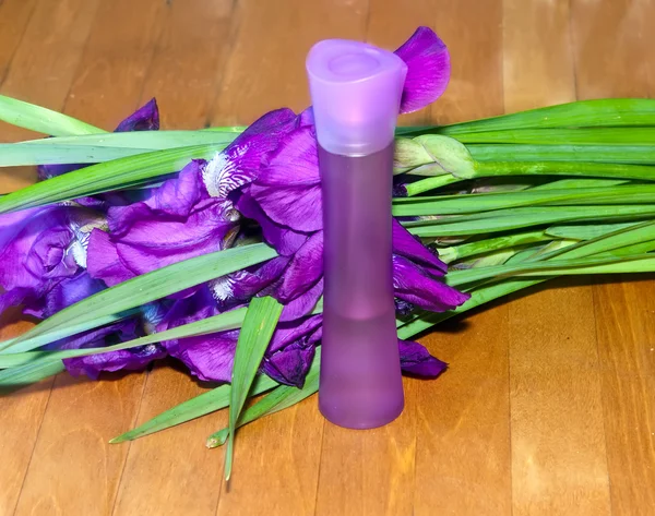 Bouquet of irises and cosmetic bottle — Stock Photo, Image