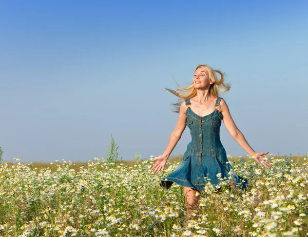 Den glada unga kvinnan i fältet för camomiles — Stockfoto