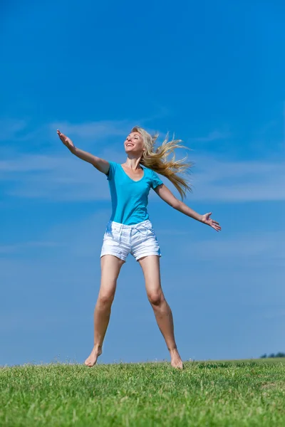 Die glückliche junge Frau springt auf das Feld — Stockfoto