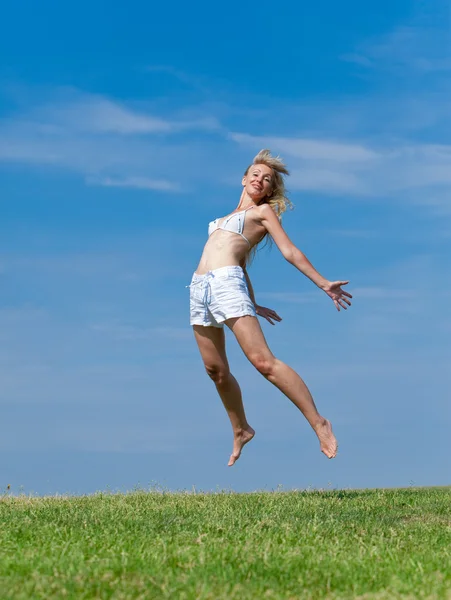 Die glückliche junge Frau springt auf das Feld — Stockfoto